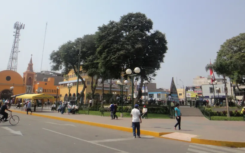 Plaza de armas de Huaral con su iglesia, árboles y vecinos paseando