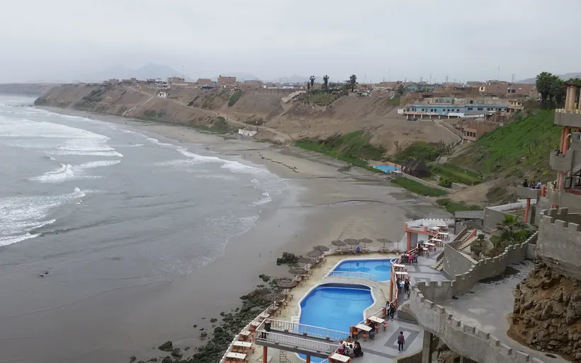 Bahía de Chancay: playa de arena, oleaje y el pueblo sobre los acantilados